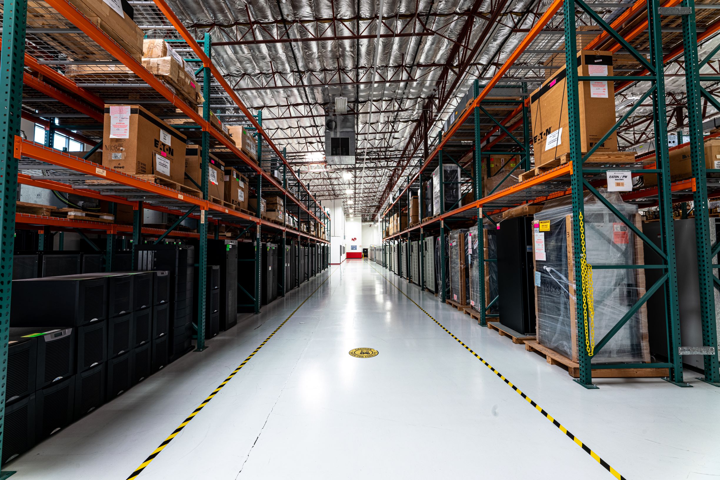 A row of equipment in a warehouse with a yellow and blacked striped line on the floor