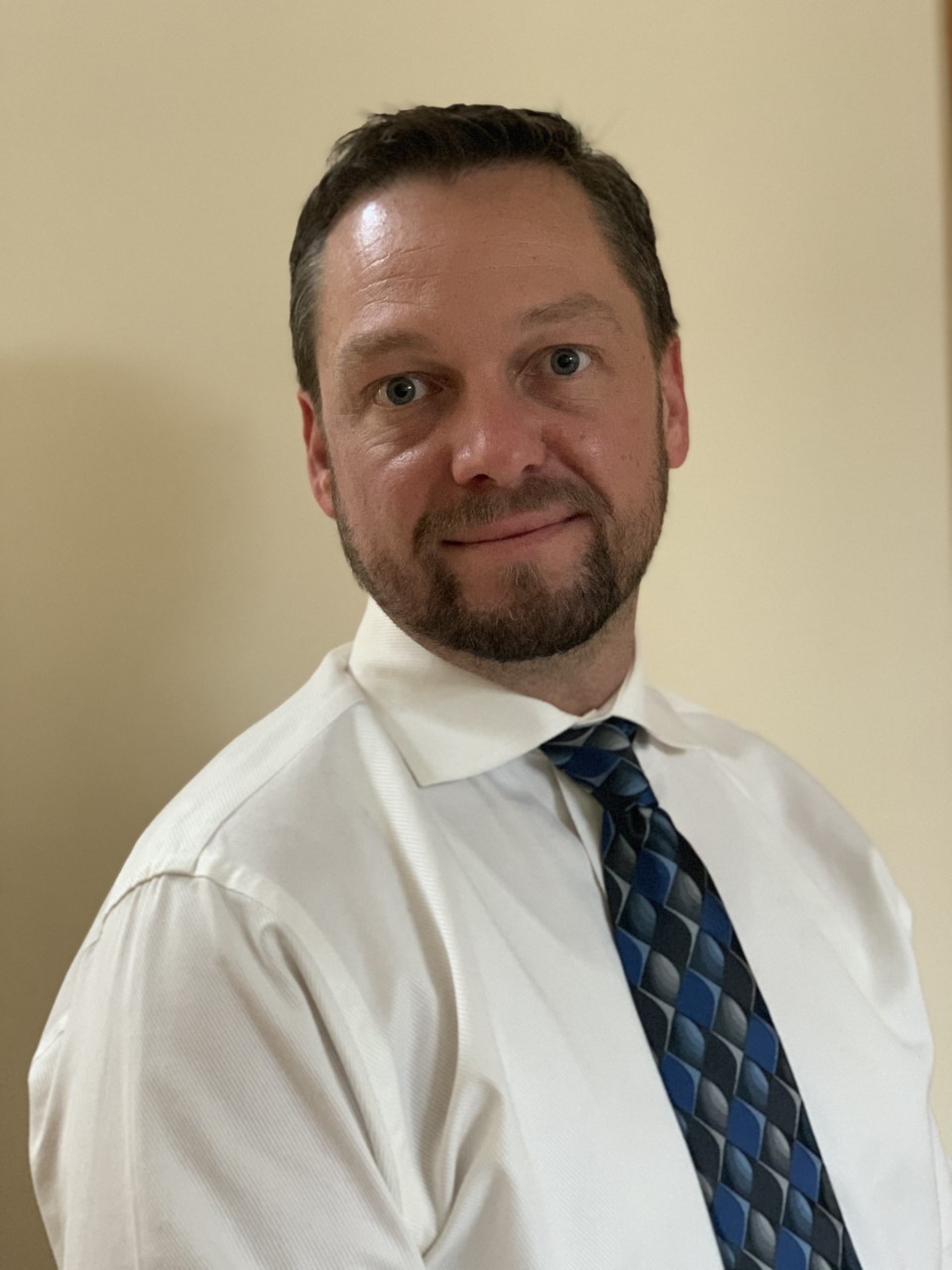 a man with a beard wearing a white shirt and blue tie